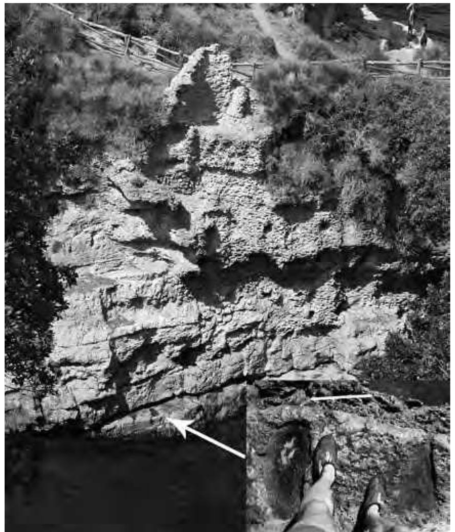 Fig. 23. Traces [at arrow] of acolossal bronze statue inthe inner port (cf. fig. 14) (© W. Filser, Winckelmann-Institut, Humboldt-Universitat).  the central axis of the N fagade, ending on a platform which contained a niche, the lower part of which is carved into the rock running along the border of the garden. Although virtually nothing of this upper ramp has survived destruction by the sea, its existence is attested by the inclined vault that came down from the quadriporticus.°! If one continued along the two lateral ramps (parallel to the fagade) running above each other, the garden could be reached either by a central stairway or by way of two final steps in its SW comer. As a result of this elaborate system of stairways and ramps, the W side of the N facade must have been an impressive sight from the garden as well as from the sea.** This also sheds light on the twofold layout of the N facade: while its E side is characterized by a sequence of finely decorated rooms with differing ground plans that seem to hover above the apse- shaped bedrock (fig. 4), the W part consisted of simple service rooms that were hidden behind the monumental triangle formed by the ramps in front of the artificial garden. 