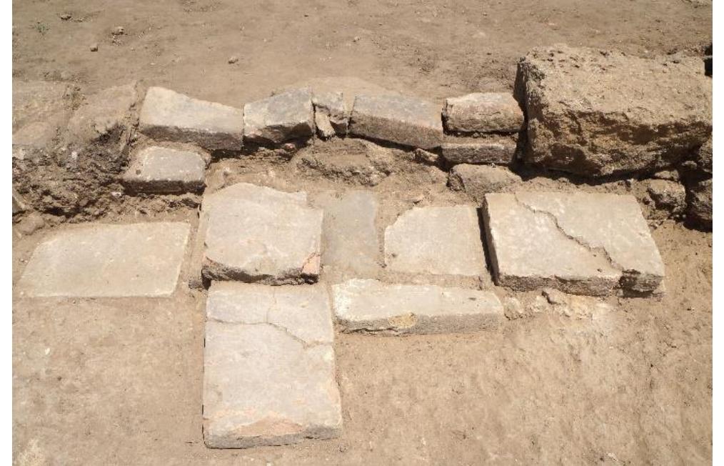 Fig. 25. Doorway between Walls H and H1 leading from Plateia B into Room 2a, looking north.  R. Souza — A. Walthall — J. Benton — E. Wueste — A. Tharler — B. Crowther — C. Schirmer e Preliminary Report on the 2016 Field Season of the Amet Excavations at Morgantina: Contrada Agnese Project (CAP)  A series of stones laid in a line between Rooms 10 and 11a and at the level of the Room 10 floor surface marked the transition from one room to the other (fig. 26). These stones created a step that negotiated the small difference in floor elevations from Room 10 (6043075 at EL 602.69-602.85 masl) down into Room 11a (60438090 at EL 602.44-602.67 masl). The boundary between those rooms was further defined by the short spur wall (Wall R) which extended 0.54m south from the stone pier, and by the placement farther south of a column formed by square brick drums, two of which were preserved in situ with their plaster facing (2.17m from the center of the pier to the center of the new column base). Neither Room 10 nor Room 11a were excavated below the Phase 3 surfaces, and both will be further investigated in future seasons. Lying on the packed-earth surface in Room 10 (6043075) we recovered a Roman silver quinarius (inv. 16-712), whict this coin was found below a well-preserved tile fall layer, occupation-related activity here before the collapse of th  