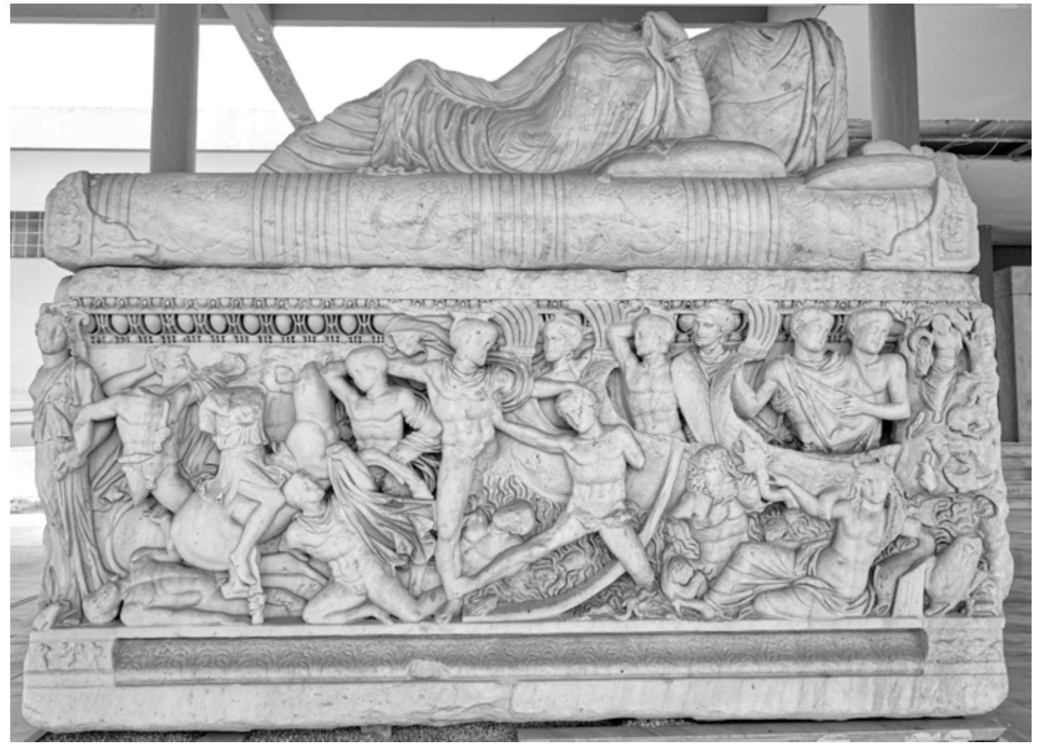 Fig. 11: Thessaloniki, Archaeological Museum Inv. 1246 (Kintrup 1999, no. 218). Attic sarcophagus depicting the battle at the ships at Troy on the front and the left small side. The identification of the typified warriors and groups is uncertain; the central group may show the victorious Hector battling a Greek, while Achilles and Patroclus are standing in the ship. The right small side shows the seated Orpheus, the back the Caledonian boar hunt. The kline lid depicts a couple in a common scheme. Ca. 240-250 AD (Photo: author).  depicting the battle at the ships at Troy on the front and the left small side. The identification of the 