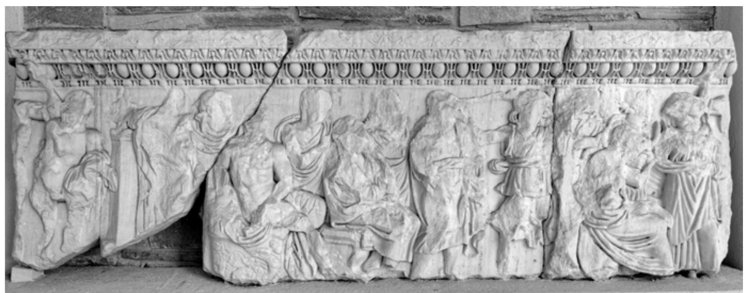 Fig. 12: Thessaloniki, Archaeological Museum Inv. P116. Attic sarcophagus with preparation of the sacrifice of Iphigenia in Aulis (2). The figures on the fragmented sarcophagus front, framed by two corner figures, have been identified by Th. Stefanidou-Tiveriou as (from left to right): Talthybios, Odysseus, Diomedes, Achilles (seated), Orestes, Agamemnon (seated), Menelaos, Calchas, Artemis (with torch and bow), Iphigenia (seated, with sacrifical attendants behind her), Clytemnestra. Early 3rd cent. AD (Photo: author). 