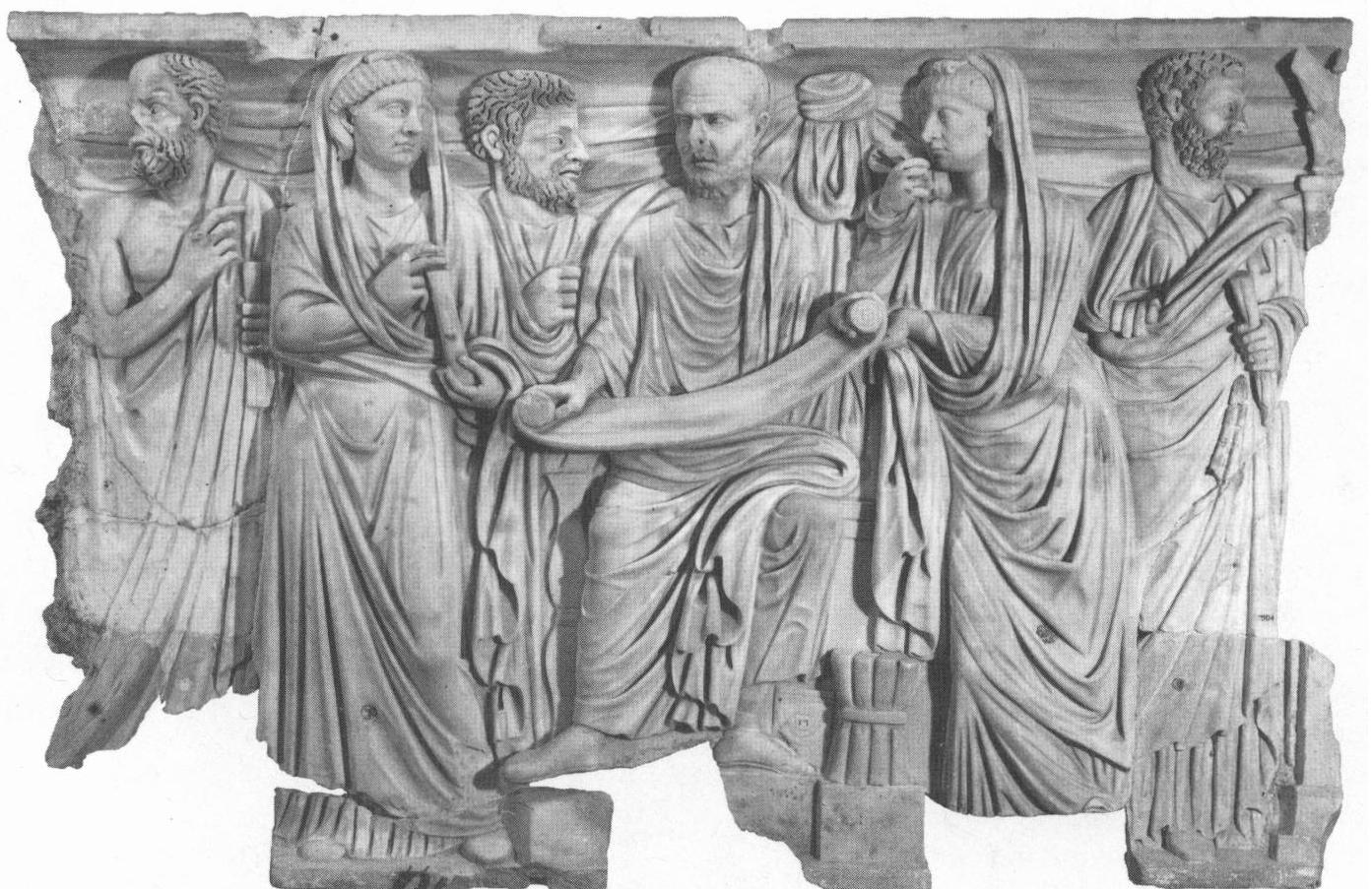 Figure 8. So-called “Plotinus-sarcophagus,” ca. 280 c.e. The fragment of a large frieze sarcophagus shows its patron seated frontally, with open bookroll. He is surrounded by two female family members (portraits) in the guise of rather “matronly” Muses, and three philosophers in the background (with traces of the original paint in the hair). The philosophers are distinguished by their dress and physiognomy; the left resembles Socrates. In the upper-right corner, a sundial. The garment of the lateral figures has been recarved from the thighs downward; the philosopher on the right must originally have been intended as a female figure. Photo: Musei Vaticani, Archivio Fotografico, Neg. N. XXX.10.1. 