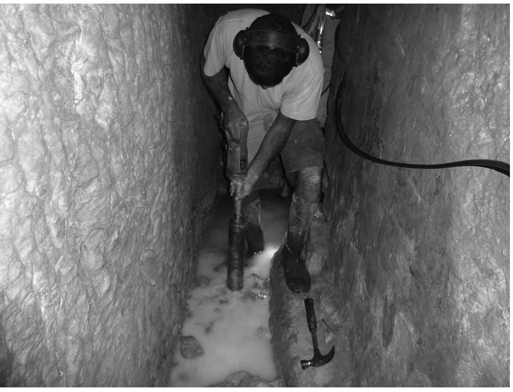 FIGURE 10.14 Joweizeh spring. Drilling a core at the bottom of the spring tunnel. (Photography by Yechezkel.)  From the entrance hall, built within the Iron Age fortifications, you enter an inclined stepped tunnel approximately 45 m long (Pritchard 1961, 5). This tunnel does not intersect ancient layers. At the beginning, the tunnel is covered with stone slabs, soon becoming entirely hewn in the bedrock. The tunnel ends in a large reservoir chamber (12 m length and 3 m width). The chamber was sup- posedly open toward the surface in times of peace, but during times of war, a built stone wall 75 cm 