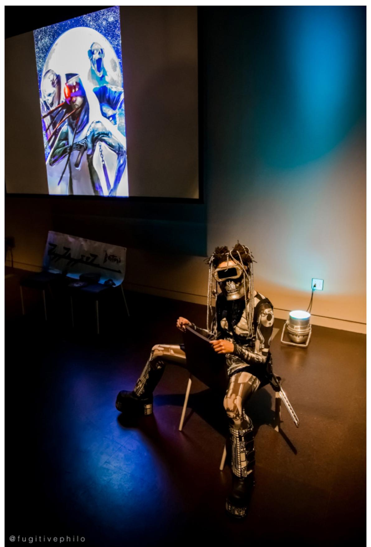 Figure 5. ZiggZagg>1Z, Raging AfroSamurai Cycloptic Cyborg #8, Afrofuturist Occupation at Pomona College (2019). Photo: tobias c. van Veen.  the “radical reconstruction and decolonization of what it means to be human” (p.4). However, I want to focus on what he identifies as its “decolonization,” as a deterritorializing, deconstructive, Afrofuturist unhinging from the grounds of the “human” as default ontological and identitarian framework, thereby suspending the teleology of its “radical reconstruction.” Deviant black cosplay calls into question the primacy of the human as the ontological foundation of identity. Deviant cosplay in general also means that the white privilege of cosplay —the privilege to perform any character as white insofar as whiteness is scripted under racializing assemblages as tabula rasa and master subject—encounters and participates in the cosplay of deprivileged characters. I want to suggest that through cosplay, questions of gender, race, ableism and white privilege are themeatized beyond allegory and representation in a potentially transformative experience of becoming-other, and doing so, at the limit, calls into question nascent structures of privilege amongst its participants.  