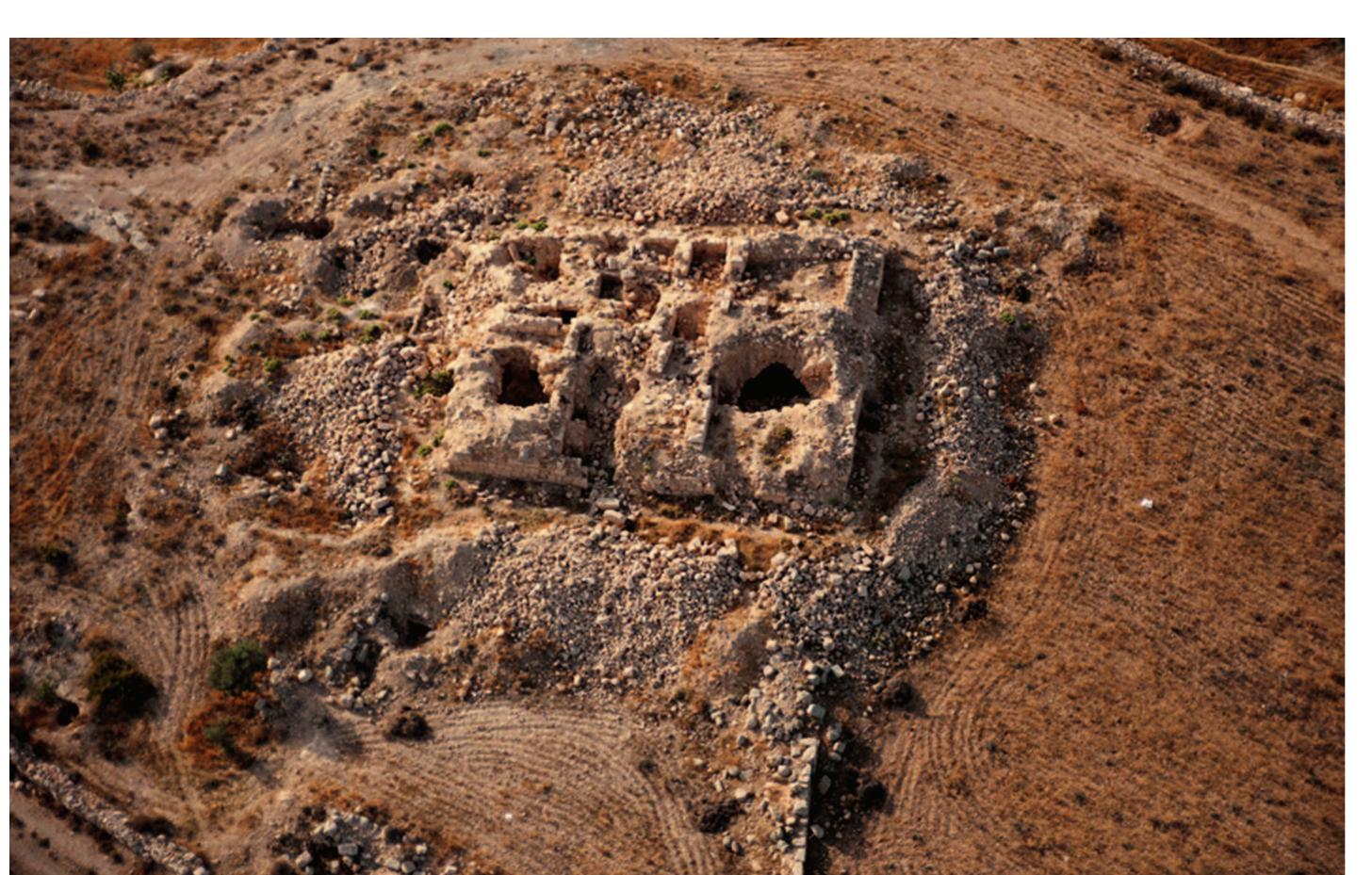 Fig. 2. Aerial view of the site (photo by |. Ruben; APAAME 20151013 IAR-0090 Courtesy of APAAME)  ‘The most urgent aim was to document the masonry structures of Qasr ed-Deir and to record its detailed plan. In accordance with that, photographs of the building (to be used for a photogrammetric documentation and processing) as well the measurements (already in the official Jordan grid system) were taken. All of the spaces and rooms on both levels have been given identification symbols (0A, 0B, 1A, 1B etc.) to be used in further research. The detailed photogrammetric documentation was done for all facades of the building, surfaces and walls (as well as floors of its first floor and for two vaulted rooms of the ground floor). Documentation of smaller rooms and spaces of the ground floor — some of them discovered during works in 2017 — was carried out using traditional methods. Thanks to the documentary component of the works, the first preliminary plan of the structure (Fig. 3-4) was prepared and a basic 3D model created. Along with the  documentation some initial archaeological activities were undertaken.  ‘The most urgent aim was to document the masonry structures of Qasr ed-Deir and 