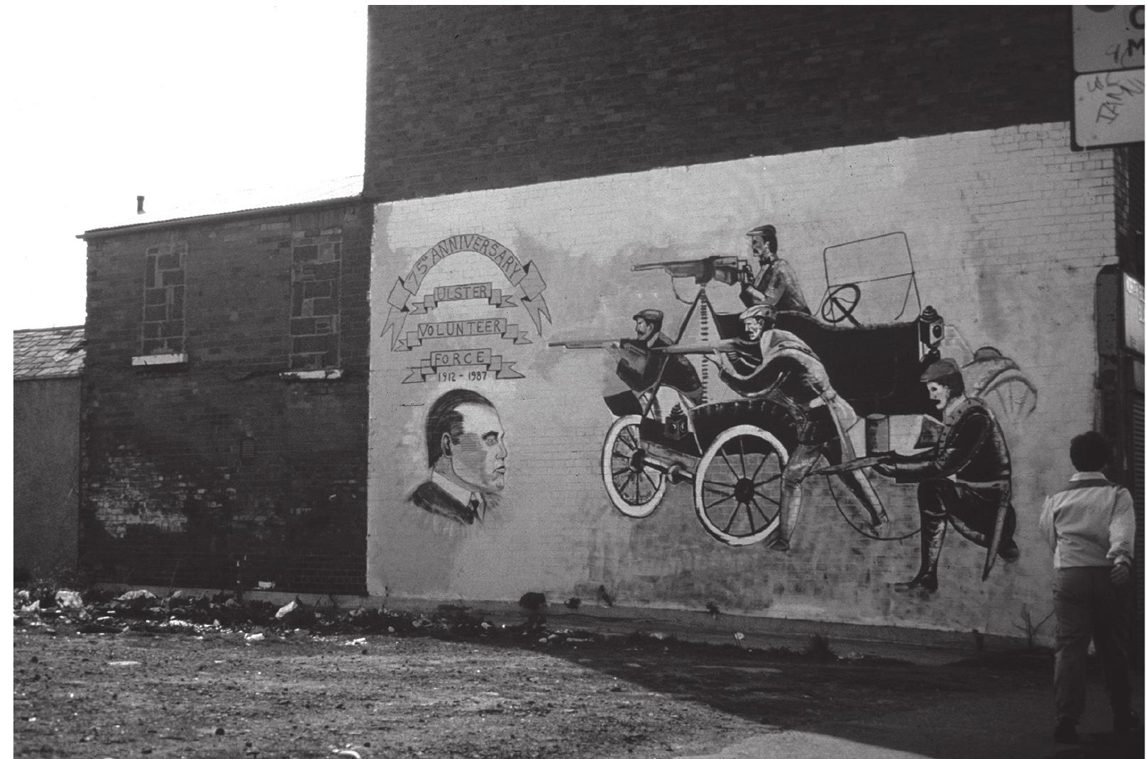 Fig. 4.2: Mural of the Motorised Division, Ulster Volunteer Force, 1912. Shankill Road, Belfast 1987 (Rolston 1991: 44). Courtesy of Bill Rolston.  Following the start of the troubles in the late 1960s, images of King Billy in the Loyalist areas began gradually to be supplemented and supplanted by new images Rolston 1991: 31-32): among them, the foundation of Carson’s Ulster Volunteer Force at the time of Asquith’s Home Rule Bill in 1912 (Fig. 4.2), and the legitimate and wholly patriotic part the UVF, as the 36th Ulster Division, played in the battles of the Western Front in the First World War (Rolston 1991: 44-45). Such images were often juxtaposed to the paramilitary image and activities of the UVF’s murky ‘reincarnation’ in the late 1960s; and the juxtaposition of these contemporary and near-contemporary images - one strictly contemporary, the other set within the three generations or so which bound historical memory - served the purpose, by association, of legitimising the contemporary UVF and its activities (Rolston 1991: 45). At the same time, these were images with which only a section of the Loyalist community as a whole could identify unambiguously - above all, those who were members or supporters of the activities and ideology of the contemporary paramilitary organisations. A contrast that  YS  