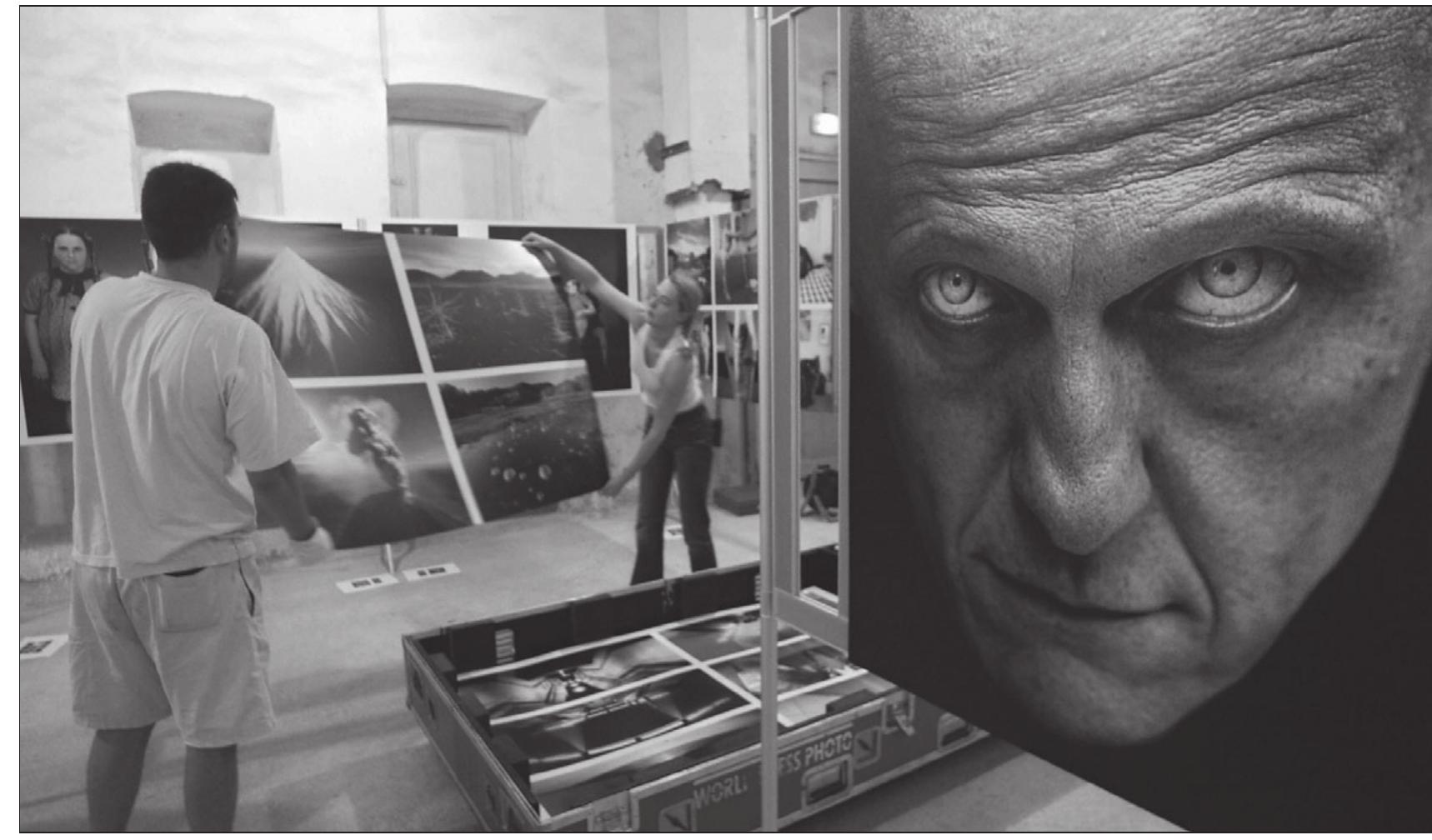 Workers display last prints at Minimes monastery in Perpignan, France, ahead of the 16th edition of the international photo- journalism festival, Visa Pour L'lmage, held from August 28-September 12, 2004. Photo courtesy Raymond Roig/AFP/Getty Images  a I a ae  On the last night of Visa Pour L'Image 2004, the show culminated in seven stories on Iraq, the single largest story for the previous year’s press coverage. The very first set of images was titled “Iraqi photogra- phers.” The festival director spoke before the series was screened.  The biography on his agency’s website tells us Paolo Woods was “born of Canadian and Dutch par- entage in 1970. He grew up in Italy and now lives in Paris. Paolo Woods worked as a photographer in adver- 