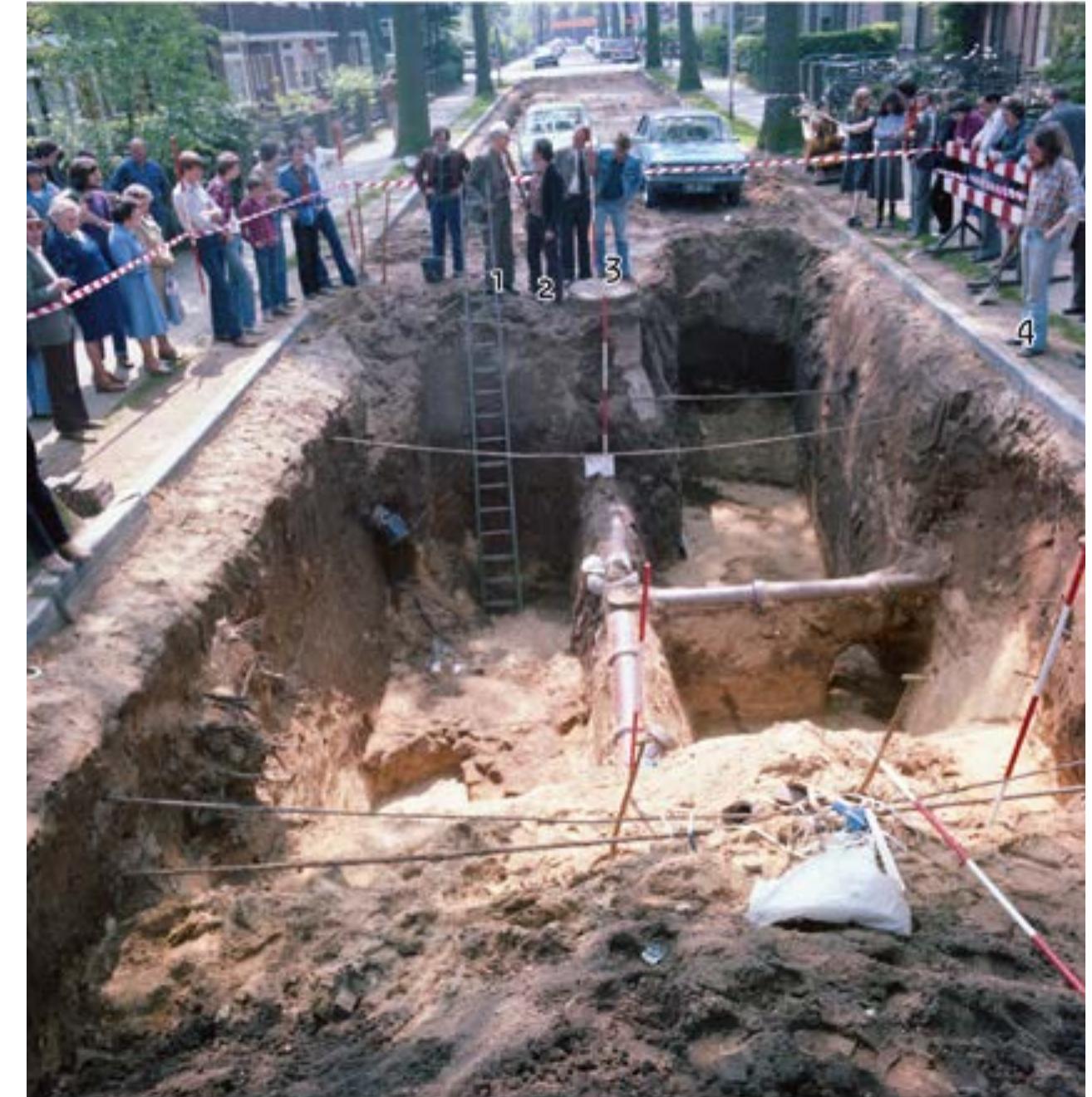 Fig. 6 Nijmegen. Amphitheatre: north arena wall. Trench 132: Level 1 from the north, showing the foundation of the arena wall; a large block of tuff stone lies to the left of the foundation (Drawing 1087). Among the visitors: 1. Prof. Jules Bogaers (Catholic University Nijmegen); 2. Klaas Greving (ROB); 3. Ben de Wit (De Wit Company); 4. Jan Thijssen (ROB) (photo: S. Kuppens, ROB). 