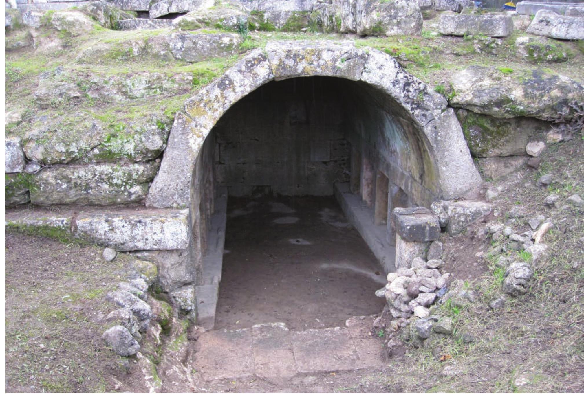 The tomb of Charmylos on the island of Kos. (Photo by V. Christopoulou.)  Other features of the natural landscape, such as trees, herbs, and shrubs, were also associated with death and the dead. These were substantial parts of the burial ritual or were involved in other ritual practices. Certain kinds of herbs and shrubs like oregano have been considered to possess particular properties appropriate to the rite of burial or to avert death.“ Several evergreen and fruitless trees, such as pine and cypress, or even hyakinthus, conveyed eschatological symbolism and were largely associated with death, the cult of Pluto, and other deities related to the Underworld (Ov. Met. 10.106; 10.162; see also de Vries 1974: 125, 475; Smardz 1979: esp. 11; and Birge 1994). Trees like these probably formed the garden of the Charmylos Tomb on Kos (ca. 300 BCE; see Fig. 9; Schazmann 1934), or those  around the tombs in the Roman period (Grimal 1983: 59-60, 172-73, 322; Purcell 1987: 188). Interestingly, in modern Greece cypress trees are the ultimate symbol  such as Nonacris in Arcadia, Acheron in Thesprotia, and Lake Avernus near Naples (Ogden 2001: 27, 43-74). Such places underline the point that while it is in their nature to stimulate feelings and memories evoking the passage of time, they simultaneously remain motionless. They articulate tensions between stasis and change, pres- ervation and decay, and the recognizable and radically unfamiliar aspects of self and other (Hallam and Hockey 2001: 51). People visiting these places were supposed to enter the Underworld and meet the dead. The physical setting would focus the participants’ attention, though to evoke this experience not only the environment, but  also the ritual must have been crucial. In the context of space, place, and landscape, performative space would have been used to unpack the behavior of performers and vice versa. Yet, the ritual performed must have involved a temporarily marginal or liminal status for some or all of the participants.  Several evergreen and fruitless trees, such as pine and 