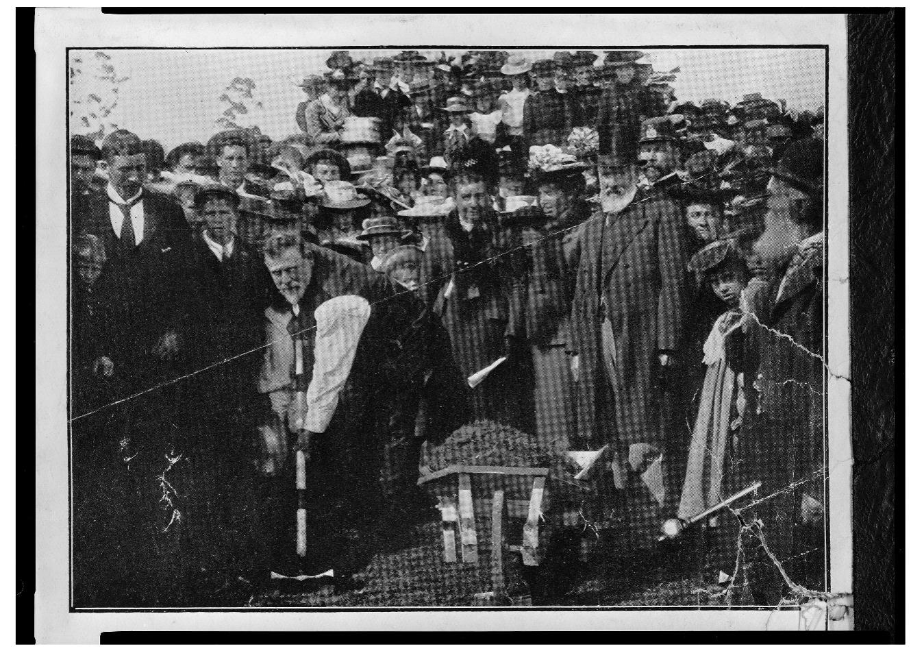 Figure 7. Prime Minister Richard Seddon turning the first sod of the Hokitika-Ross railway. Ref: 1/2-044361-F. Alexander Turnbull Library, Wellington, New Zealand.  landscape, for the benefit of all.  While arguing for cooperat  ©  ion, Lloyd gave the statesman-politician prime  position as the agent of social and technological progress. In Lloyd’s hagio- graphic depiction, Richard Seddon, the Minister of Public Works, embodied the state-as-builder.°* Seddon’s background in mining legitimised this char- acterisation. Born in England, he had emigrated first to Australia where he  worked in the Victorian gol where he entered politics.*°  dfields before travelling on to New Zealand A charismatic populist, Seddon became the  Premier (New Zealand’s highest elected official) in 1893. His two nick- names — “Digger Dick” and “King Dick” - epitomised his dual proletarian  and autocratic reputation. Wi physical presence, Seddon ex  th his larger than life personality and imposing ploited his own image. Travelling all over the  country to visit Public Works construction sites, he placed himself at the  centre of elaborately staged  photo opportunities (Fig. 7). This image was 