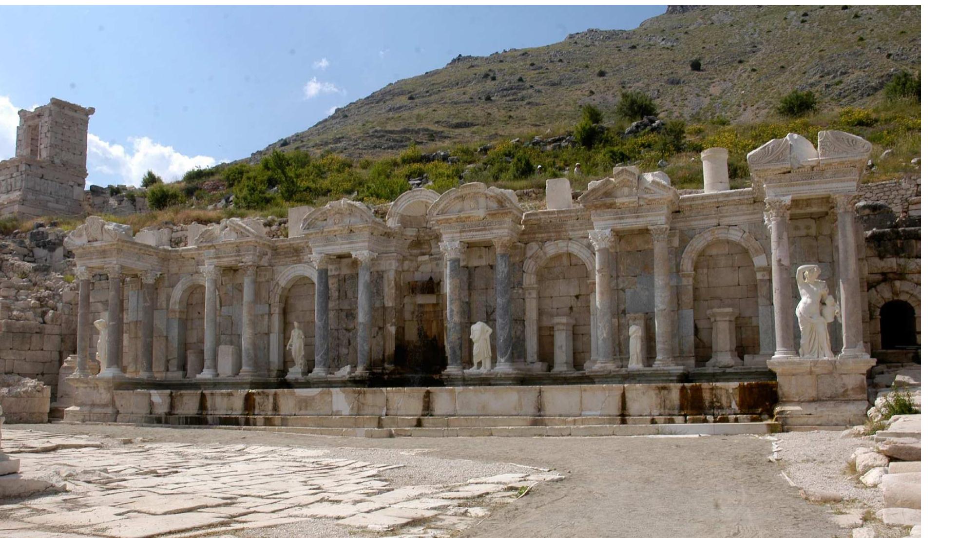 Fig. 8. View of the Antonine Nymphaeum from the southeast (Sagalassos Project).  the change and remained in use until the later 4" or even 5" century CE, as suggested by their fill (Talloen - Poblome 2016: 138-139). The fountain building itself was completely dismantled up to the level of its foundations and part of the building material may have ended up in the back wall of the Antonine Nymphaeum as spolia, as suggested above. Its substructure was partly reused as pavement in the northern part of the square as the new fountain, although substantially wider, was not as long as the old one, and thus required less space of the agora, leaving some of the remains of its predecessor exposed. In time those remains were covered by levelling deposits, laid out for the construction of a new sewage channel in the 6" century (Talloen — Poblome 2016: 145-146), obliterating the  last traces of a building that once was the splendour of the agora. ee ok ee i, oe oc i: © i: i. oS ee oc: i, oc) es ae 