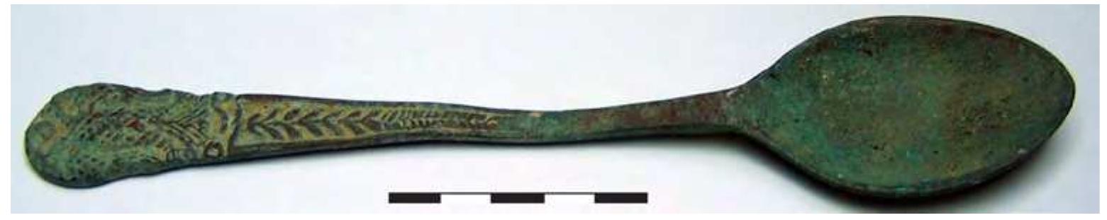 and corresponds to types occasionally found across Europe during the late Middle Ages (Fig. 1).” It has a total length of 14.9 cm and the dimensions of its bowl are 3.2 by 2.9 cm. It is typically similar, in terms of the shape of its bowl, with a pewter spoon, possibly of the 12th century, which was discovered during the excavation of a church in the deserted medieval village of Quattro Macine, in south Puglia, and which was adorned with Eu- charistic symbols (fish and wild creatures on either side of the tree of life).”! The handle of the spoon from Chle- moutsi castle has a flattened stem and an undecorated back. The front is divided, based on the decoration, into three sections. The first section, closest to the bowl of the spoon, is undecorated. The second -middle- section has a vegetal design inside a ribbon frame. A similar decoration is found on the handle of a spoon from London, dating back to the 14th century.” The third section, at the tip of the utensil, is adorned with a two-headed eagle with open wings (Fig. 2). The tips of its feathers are portrayed with parallel engravings and its body is covered  with a rhomboid grid. A small pellet appears between the two heads.  Fig. 1. Chlemoutsi castle, copper alloy spoon (© Ephorate of Antiquities of Ilia).  In the Middle Ages, the double-headed eagle, a well-known ancient symbol in the Near East, started to spread across Western Europe as a coat of arms, often under the influence of the Byzantine imperial court.” In a manuscript from around 1330-1340, associated with the Anjou kings of Naples, suzerain rulers of the Princi- pality of Achaia from 1278 to c. 1386, the two-headed eagle is occasionally used as a coat of arms.” From the late 13th-14th century, the double-headed eagle was used as a family emblem by the imperial family of Palaiologos and was also adopted by several powerful families, who were affiliated with the Palaiologos dynasty in various ways.” Although it cannot be ruled out that it belonged to some nobleman of Western European origin, the spoon should probably be linked to Constantine XI Palaiologos, the last Byzantine emperor (1448-1453), and his court, considering Constantine’s historically documented stay at the castles of Chlemoutsi and Glarentza from 1428 to 1432.” In any case, the object most probably had a secular use.  spread across Western Europe as a coat of arms, often under the influence of the Byzantine imperial court.” In 