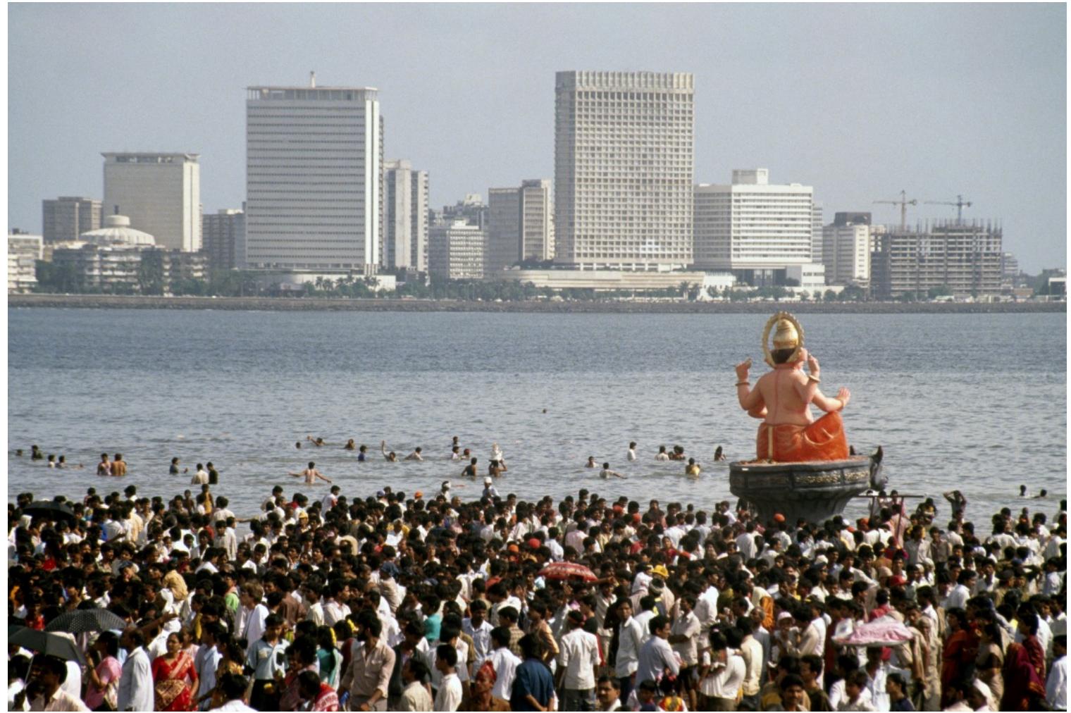 Image 4: Views of the Ganesh immersion. Here the Static and Kinetic cities are juxtaposed visually. (photo credit Rahul Mehrotra)  In Mumbai for example, the popularity and growth of the Ganesh festival has been phenomenonal.* During the festival, which occurs in August or September, numerous neighbourhoods transform temporarily with lights and decoration. New spaces are created to house the idol of Ganesh for ten days. During this festival period, the entire city at all scales (family, neighbourhood and city events) marks the celebrations. On the last day a large part of the city’s population carries the idol in long processions ultimately to be immersed in the sea. 