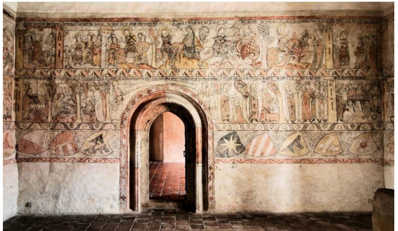 Figure 22. Jindiichtv Hradec, castle. St. George’s cycle in the palace. Paintings dated to 1338. Photo by Franti8ek Zaruba, the author’s own work.  Undoubtedly, the most outstanding example of wall painting of this period 1s foun in Jind¥ichttv Hradec (Figure 22). This is the cycle of St George, accompanied by extensiv heraldic motifs (Kréalova 1956, pp. 311-21; PeSina et al. 1958, pp. 229-47; Novy 197. pp. 179-97; 2002, pp. 34-47; Lechner 2002, pp. 48-63; Dinzelbacher 2002, pp. 64-65 Gerat 2011, pp. 175-83). The preserved inscription confirms the paintings’ date to 133: he inscription also identifies Oldiich of Hradec as commissioning the paintings: “die gemel h’(err) ulr “(ich) von den neienhausse hat haisen malen nach cristus geburt dreuzehi cdert iar im acht und dreisigiste iar” (Figure 23). As in the cases described earlier, w find these paintings in the building of an early Gothic palace, on its first floor, in a sma room which was originally covered with a flat ceiling. The paintings in the cycle of $ George are arranged in two horizontal strips, below which there is an additional one wit! heraldic decoration. It seems that the coats of arms depicted there could have represente the participants in John of Luxemburg’s crusade against Lithuania in 1337 (Novy 1971, p] 79-97). This would also explain the choice of the legend of St George: in the Middle Age his saint was considered, among other things, a patron of the fight against the pagan (although he was primarily perceived as the ideal of knighthood, making his story ver popular among knights).  