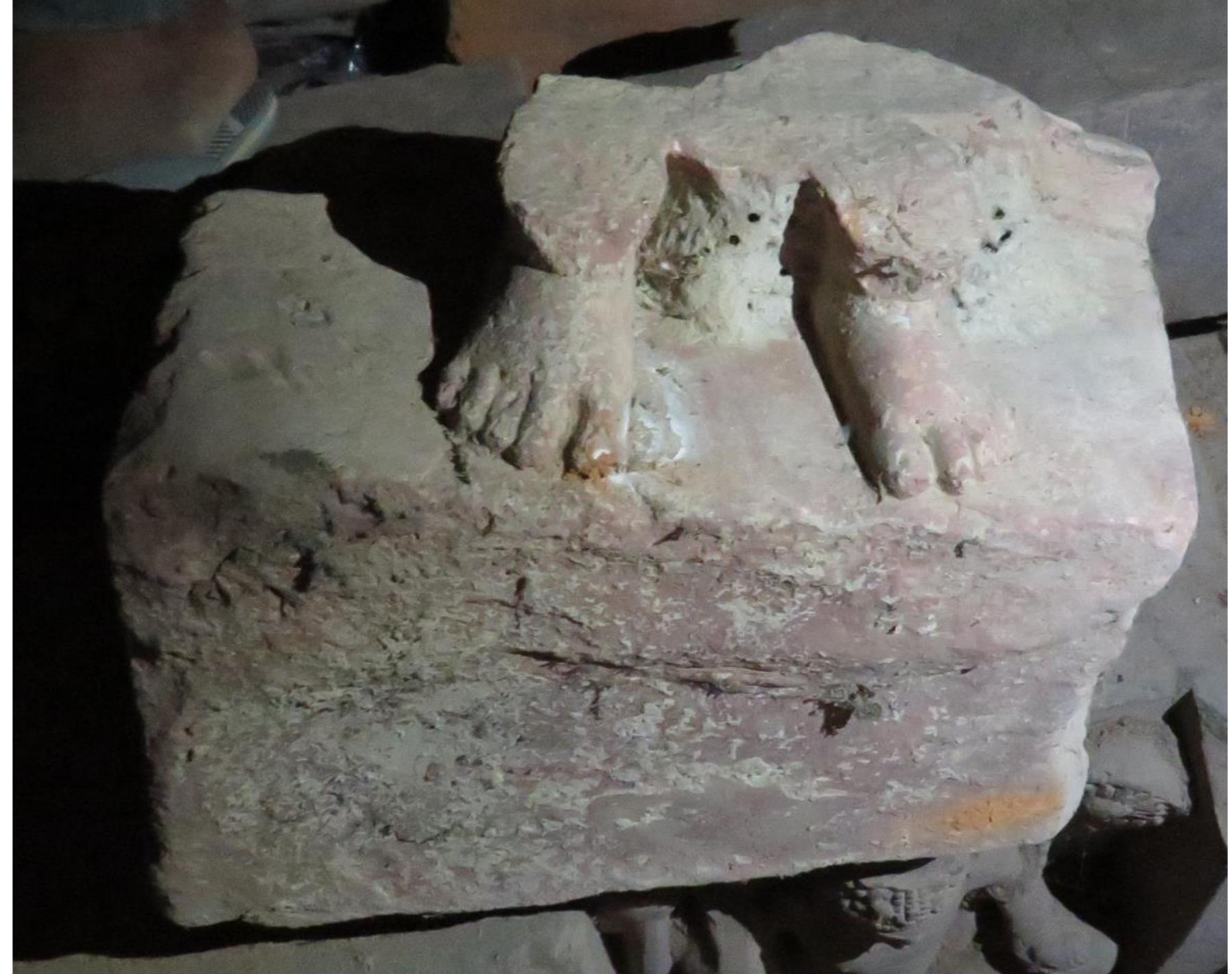 Figure 22: Lower Part of a Figure  with wristlets and a broad ekavali. He is scalloped border. The overall treatment of  also provided with a round halo with a this figure is so unique that it is slightly  difficult to identify its exact nature but since it appears to be a pre-stage when the  iconography of Buddhist deities evolved a  set pattern, it might be one of the earliest  examples of seated Buddhist figures in Mathura art, datable to pre-Kushan period (may be even last decades of 1*t century BCE). On the reverse side of this pillar, chaitya shrines divide the pillar into three parts. In the lower part only a shrine is visible while above it a male figure is shown standing wearing ekansika sanghati (similar to Bodhisattva figures). His left hand is placed near its waist probably holding some  object whereas it if difficult to judge the pos  ture of his right hand. Not many details are  identifiable in this figure since the surface is quite corroded. In the upper panel, a  Bodhisattva is shown standing possibly ho his right hand is in abhaya mudra with sligh a thick fold of which is arranged over his le A round halo with scalloped border indica like hair is tied in a top bun. The overall Maitreya Buddha and again confirms its  ding a water-pot in his left hand whereas tly angular position. He is wearing a dhoti, ft hand. He is adorned with a broad ekavali. tes his divine status. His slightly wavy jata treatment of the figure indicates it to be pre-Kushan date. Unfortunately, in recent  years the railing pillar has got broken in negligence of local staff.  to two pieces and much corroded due to 