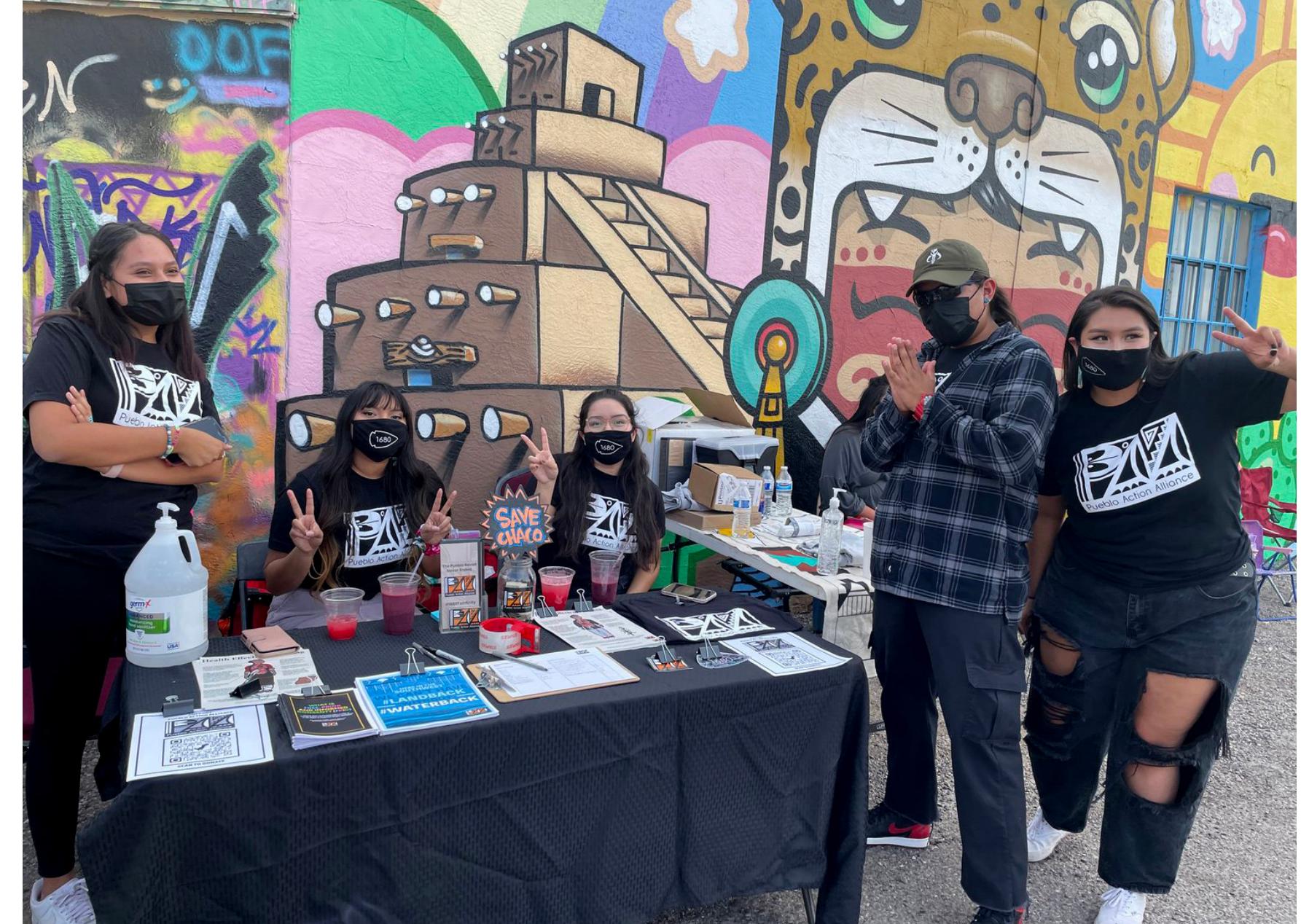 Alyosha Goldstein (he/him) is a professor of American studies at the University of New Mexico. He is the author of Poverty in Common: The Politics of Community Action during the American Century, editor of Formations of United States Colonialism, and coeditor of For Antifascist Futures: Against the Violence of Imperial Crisis. He also currently serves as an elected board member of the SouthWest Organizing Project.  Fig. Julia Bernal, Alliance Director, speaking at the Red Road to DC totem pole ceremony and delivery to the Department of the Interior, July 29, 2021./ Courtesy of Pueblo Action Alliance.  Julia Bernal (she/they) is from the Indigenous Nations of Sandia Pueblo and Yuchi and is the Director of the Pueblo Action Alliance. She is pursuing dual masters degrees in Water Resources and Community and Regional Planning. She serves on the Natural Resources Committee for the All Pueblo Council of Governors and the New Mexico Climate Change Task Force Technical Advisory Group.  Fig.2 “Hereinthe Southwest, We can't have #LANDBACK without #WATERBACk” campaign graphic that visualizes Pueblo Indigenous people's relationship with water. / Courtesy of Pueblo Action Alliance.  Fig.3 Pueblo Action Alliance Youth Organizers at their community event, “Pueblo Youth Revolt,” to honor the 341st anniversary of the 1680 Pueblo Revolt and educate the community on their campaign “Youth to the Front!,” August 10, 2021.” / Courtesy of Pueblo Action Alliance. 