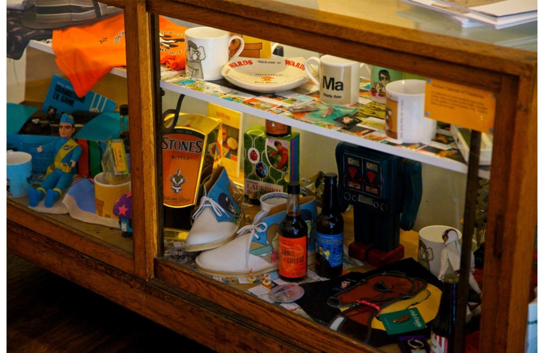 Fig. 6.23: Pete McKee’s cabinet of curiosities featuring his limited edition Clarks Desert Boot collaboration. October 2014, photograph by Steve Pellegrino.  6.21: Artist Pete McKee in his gallery A Month of Sundays in Sheffield. December 2014, own photograph.  A Lambretta Scooter in Pete’s Sheffield gallery featuring his iconic characters. Photograph by Steve Pellegrino. 