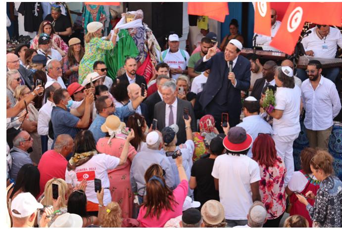 Tolerance speech of imam Hassen Chalgoumi, 2022. Photograph © Manoél Pénicaud.  Another significant moment of poly-rituality occurred in 2022 (repli- cating a performance that had already occurred in previous editions). During one of the musical interludes that punctuated the auction and off- cial speeches, a Jewish pilgrim took the microphone and began to sing in a very solemn way the Muslim call to prayer “Allah Akbar” (God is Greater), then “Sh’ma Israel” (Hear, O Israe/), the well-known centrepiece of the morning and evening Jewish prayer services, then “Adonai” (My Lord), and again “Allah Akbar” in a very vibrant and emotional voice. His perfor- mance was obviously planned but it looked improvised, and the audience was surprised at first, before applauding and welcoming this call for peace.  A different initiative of poly-rituality occurred in May 2019. when the 